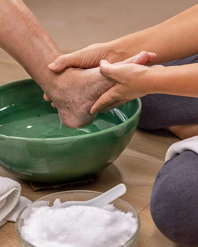 Eine Pflegekraft macht einer Patientin mit diabetischem Fuß ein Fußbad.