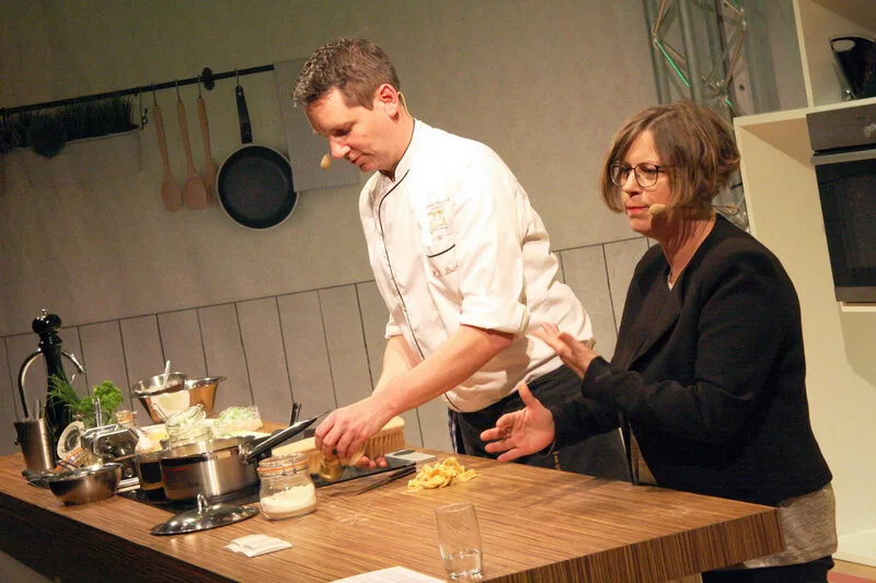 Die Moderatoren der AOK-Kochshow in Friesenheim kochen vor Publikum.