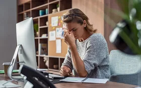 Eine Frau sitzt erschöpft am Arbeitstisch 