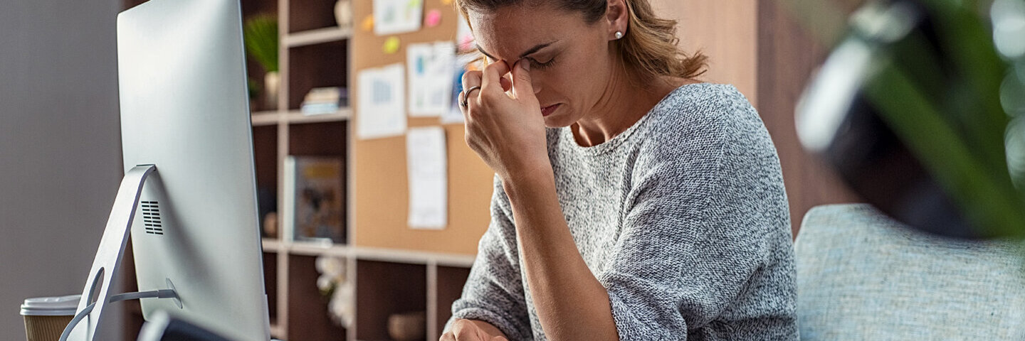 Eine Frau sitzt erschöpft am Arbeitstisch