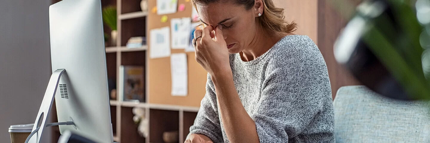 Eine Frau sitzt erschöpft am Arbeitstisch 