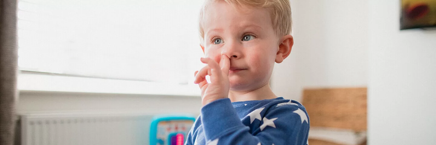 Kleiner Junge popelt in seiner Nase.