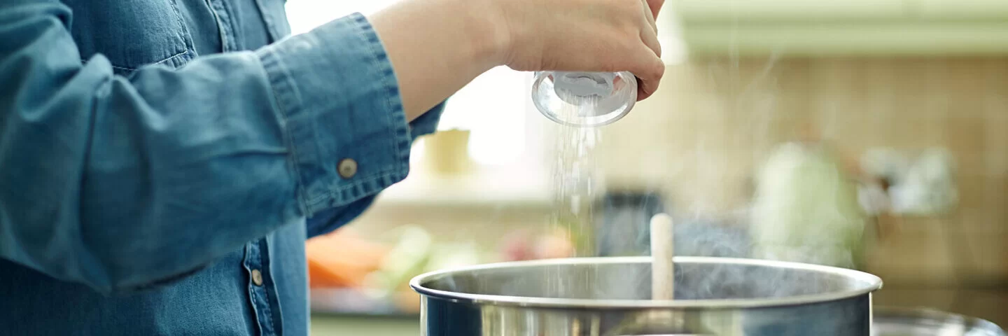 Eine Frau salzt beim Kochen.