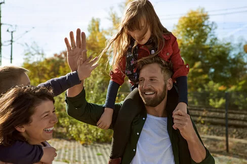 Eine Familie ist draußen; alle lachen und klatschen in die Hände. Sie wissen, dass die AOK für ihre Leistungen zahlreiche Auszeichnungen bekommen hat.