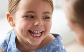 Lachendes Mädchen wird von Ärztin untersucht.