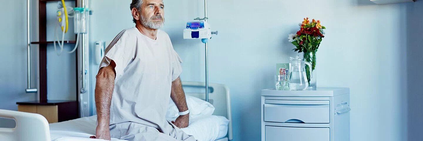 Ein Mann sitzt auf einem Krankenhausbett und denkt über multiresistente Keime nach.