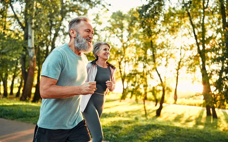 Ein mittelaltes, sportliches Paar joggt im Wald.