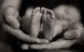 Die Hände der Mutter halten die Füße ihres Sternenkindes.
