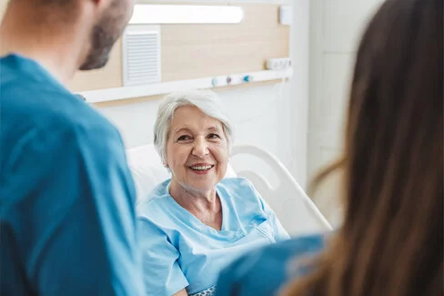 Eine ältere Frau liegt in einem Krankenbett.