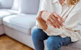 Frau leidet durch ihre Fibromyalgie unter schmerzenden Gelenken und massiert ihre Hand.