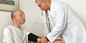 Ein Arzt misst den Blutdruck bei einem Patienten. Mit dem AOK-Curaplan Koronare Herzkrankheit, gelingt es, das Leiden besser zu kontrollieren.