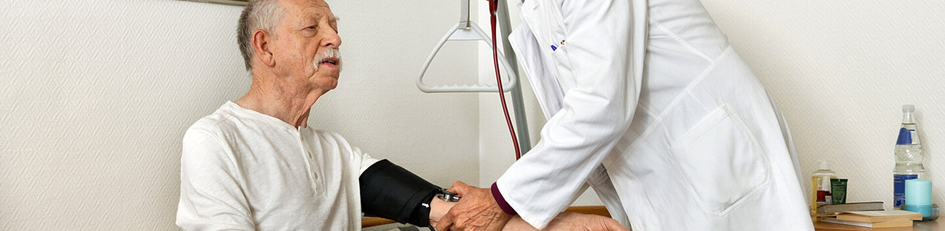 Ein Arzt misst den Blutdruck bei einem Patienten. Mit dem AOK-Curaplan Koronare Herzkrankheit, gelingt es, das Leiden besser zu kontrollieren.