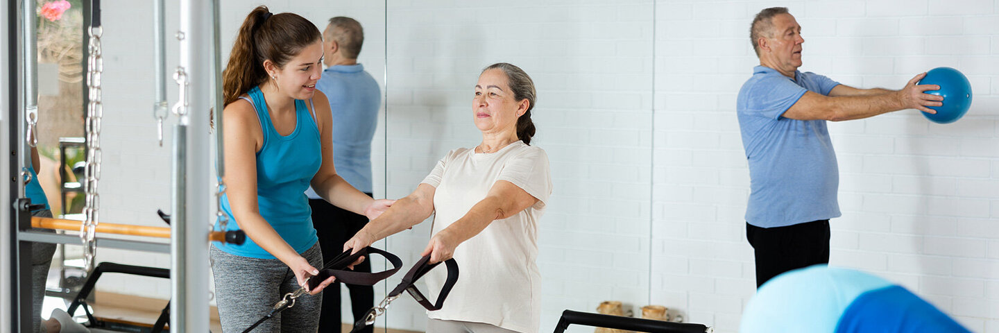 Eine ältere Frau und ein älterer Mann trainieren unter Anleitung.