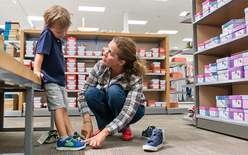 Eine Mutter überprüft im Schuhgeschäft mit ihrem kleinen Sohn, ob die Sportschuhe groß genug sind.