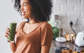 Eine Frau hält einen Smoothie mit vielen Vitaminen in der Hand.