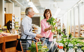Ein Paar kauft gemeinsam im Supermarkt frisches Gemüse für eine Low-FODMAP-Diät ein.