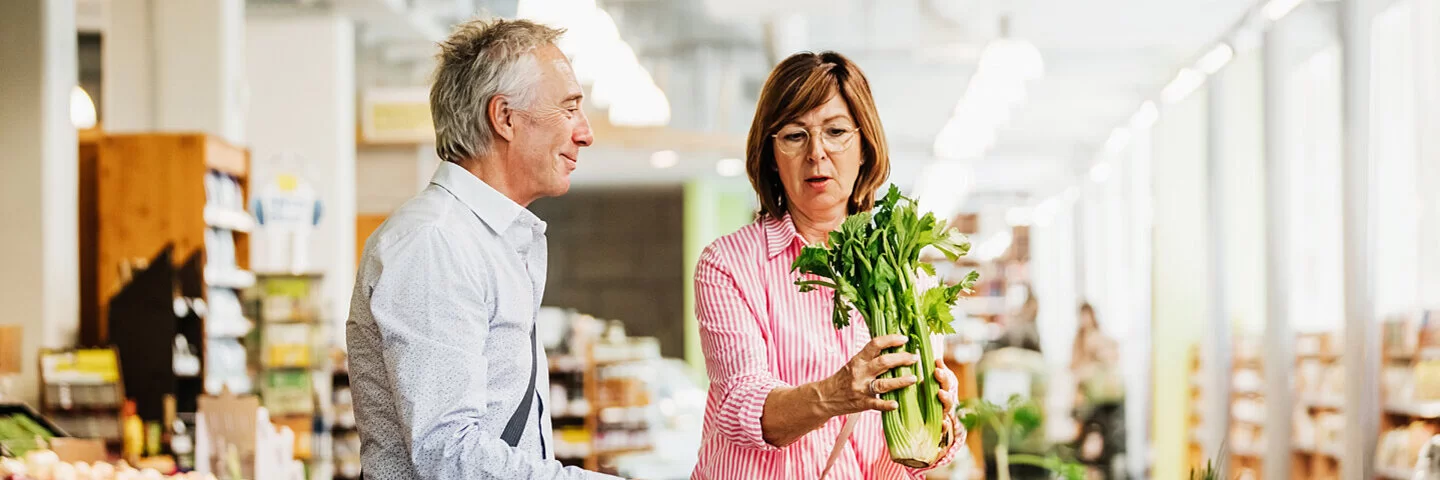 Ein Paar kauft gemeinsam im Supermarkt frisches Gemüse für eine Low-FODMAP-Diät ein.