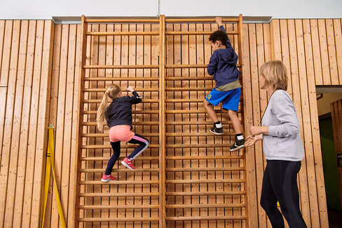 Kinder machen zusammen mit einer Lehrerin Sport. Beim Präventionsprogramm „Henrietta & Co.“ erfahren sie, warum Bewegung und gesunde Ernährung wichtig sind.