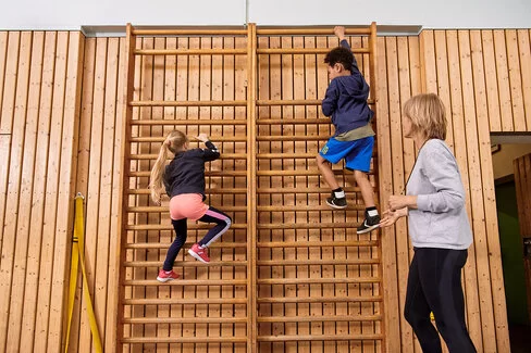 Kinder machen zusammen mit einer Lehrerin Sport. Beim Präventionsprogramm „Henrietta & Co.“ erfahren sie, warum Bewegung und gesunde Ernährung wichtig sind.