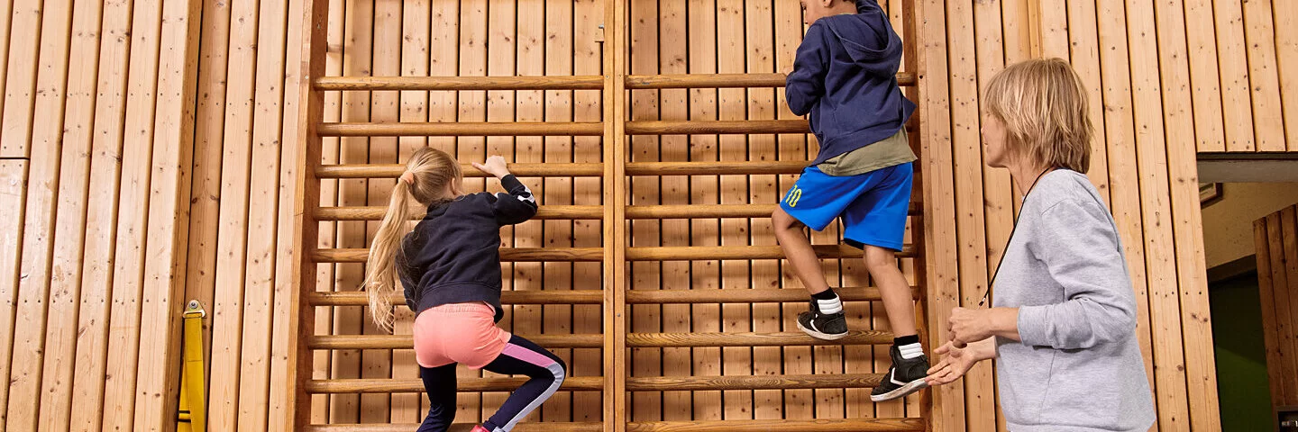 Kinder machen zusammen mit einer Lehrerin Sport. Beim Präventionsprogramm „Henrietta & Co.“ erfahren sie, warum Bewegung und gesunde Ernährung wichtig sind.