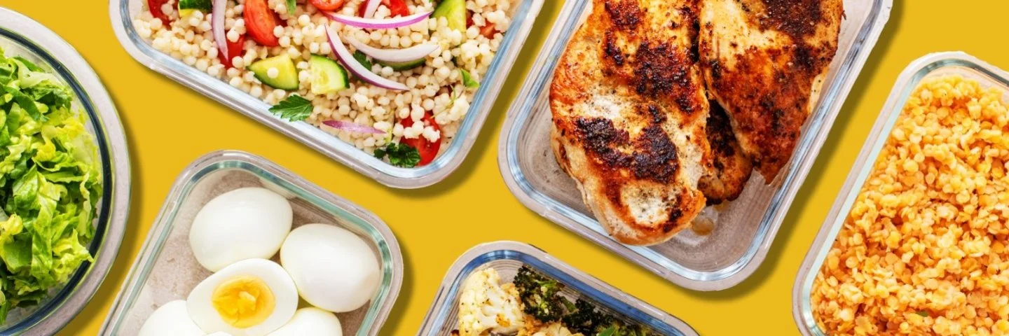 Mehrere Glasbehälter mit gekochtem Gemüse, gebratenem Fleisch, Eiern, Nüssen und Salat auf gelbem Hintergrund.