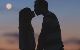 Silhouette eines sich küssenden Paares vor dem unscharfen Hintergrund eines Stadtpanoramas.