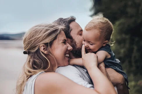 Familie mit Kleinkind kuschelt zusammen.