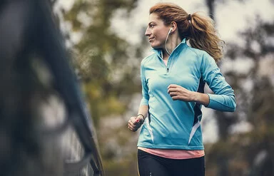 Eine Frau in Sportkleidung joggt und sieht dabei zur Seite.