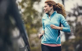 Eine Frau in Sportkleidung joggt und sieht dabei zur Seite.