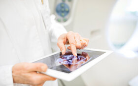 Künstliche Intelligenz: Tablet zeigt medizinischen Content, wird in zwei Händen gehalten.