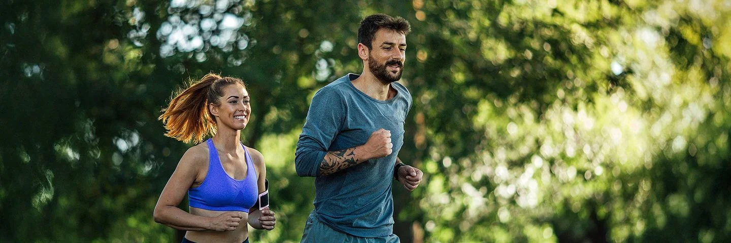 Zwei junge Menschen joggen in der Natur.