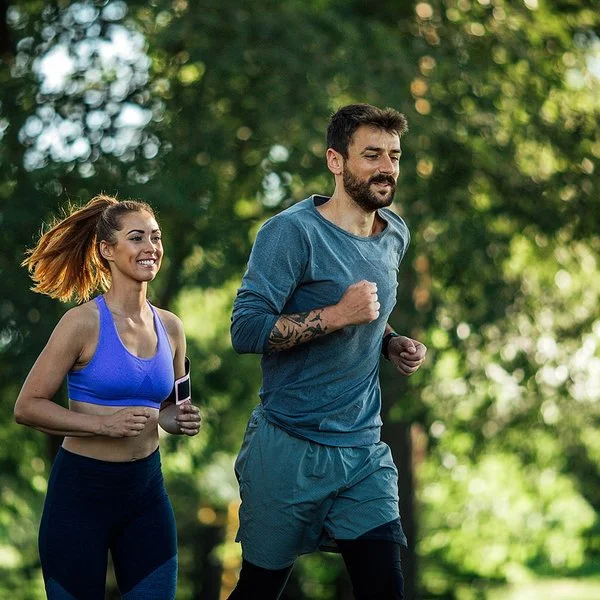 Zwei junge Menschen joggen in der Natur.