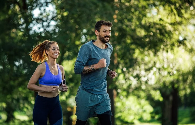 Zwei junge Menschen joggen in der Natur.