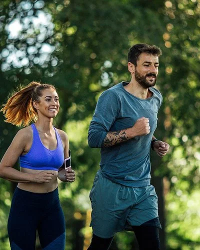 Zwei junge Menschen joggen in der Natur.