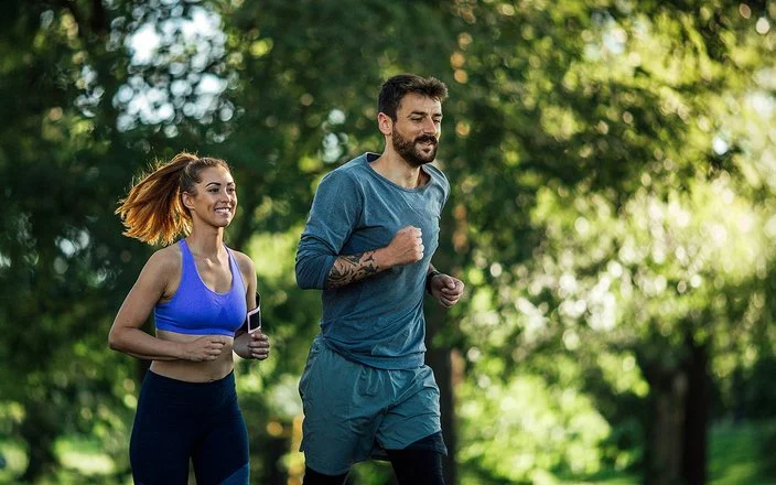 Zwei junge Menschen joggen in der Natur.