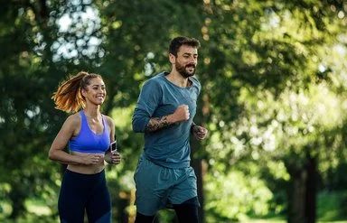 Zwei junge Menschen joggen in der Natur.
