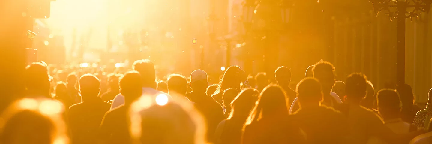 Eine Fußgängerzone mit einer Menschenmenge in der Abendsonne.