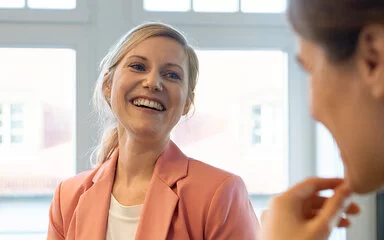 Zwei gut gelaunte Frauen sprechen miteinander. Als Berufseinsteigerinnen sind sie bei der AOK gut versichert.