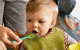 Eltern legen Wert auf eine gesunde Ernährung für Kinder und füttern ihr Baby mit frischem Brei.