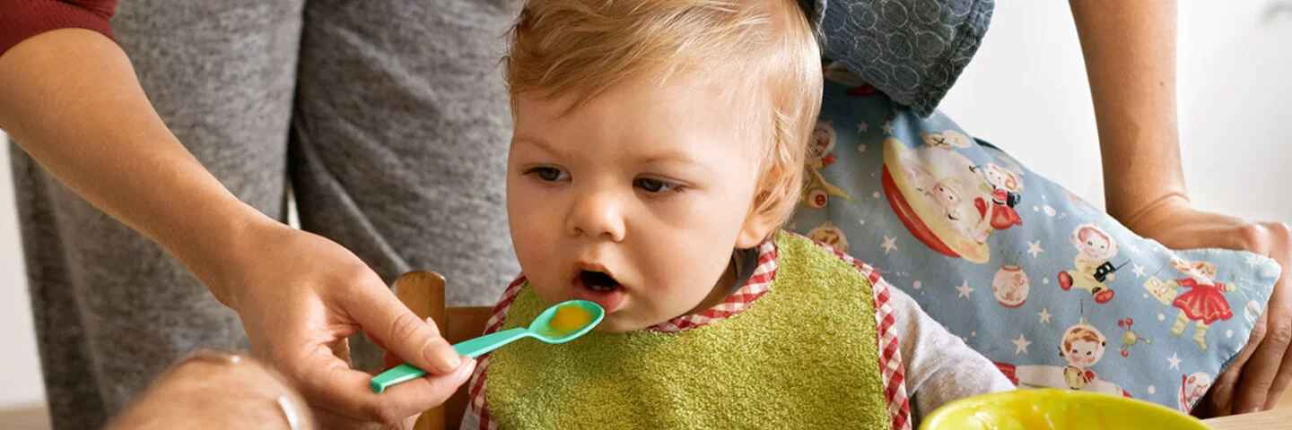 Eltern legen Wert auf eine gesunde Ernährung für Kinder und füttern ihr Baby mit frischem Brei.