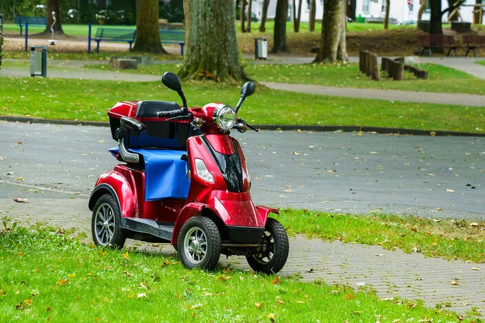 Ein vierrädriger Motoroller für Behinderte steht am Straßenrand.