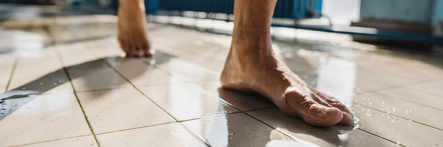 Ein Mann läuft barfuß durch ein Schwimmbad.