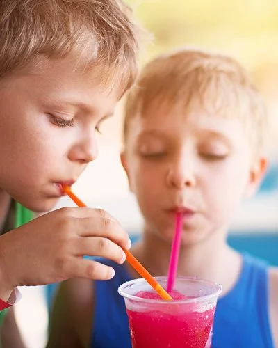 Zwei Kinder in sommerlicher Kleidung trinken mit Strohhalmen aus einem Slush-Eis-Becher.