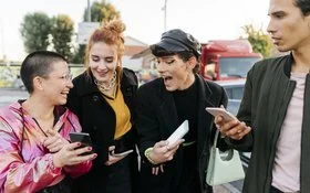 Gruppe von vier Personen steht draußen und hält Smartphones in den Händen.