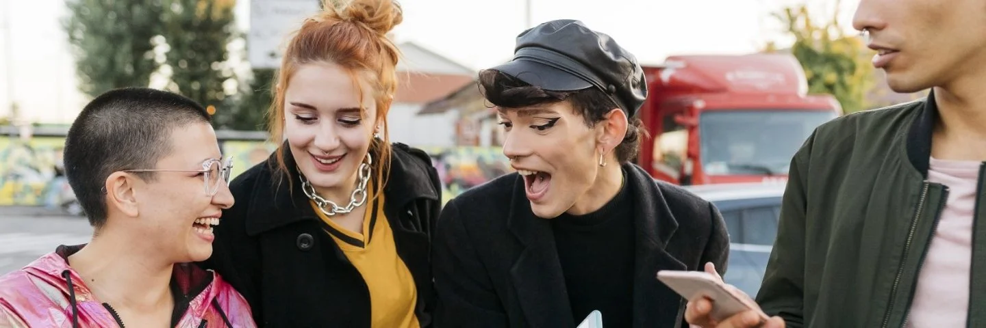 Gruppe von vier Personen steht draußen und hält Smartphones in den Händen.