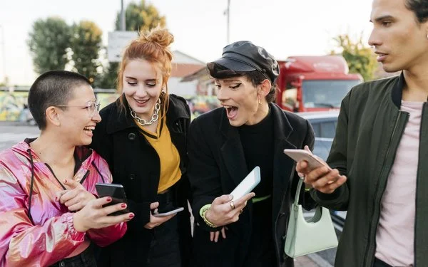 Gruppe von vier Personen steht draußen und hält Smartphones in den Händen.