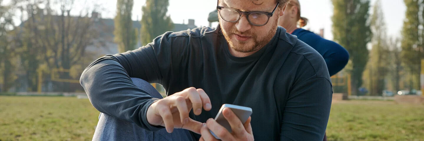 Ein jüngerer Mann recherchiert mit seinem Smartphone. Barrierefreie Angebote der AOK erleichtern den Zugriff.