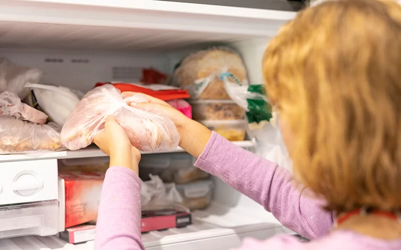 Eine Frau legt Fleisch zum Einfrieren in den Tiefkühlschrank.