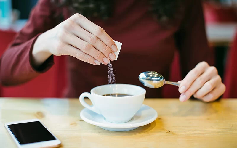 Frau gibt Zuckerersatzstoff in ihren Kaffee, ist das wirklich gesünder?