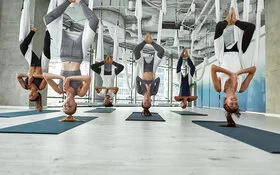 Eine Gruppe von Frauen beim Aerial Yoga in einer Halle – alle hängen kopfüber in der Luft.